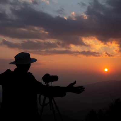 silhouette of a photographer who shoots a sunset in the mountain